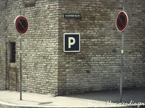 The two signs on pulls mean no parking. The sign on the building means parking. Essentially you are being told to park on the corner, but of course that is illegal in France.